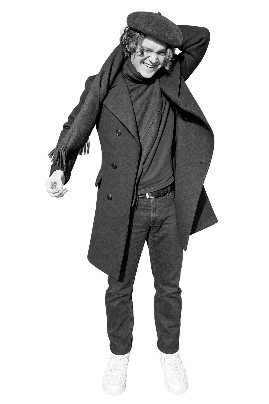 Andrew in a dark coat and beret, smiling with one arm raised